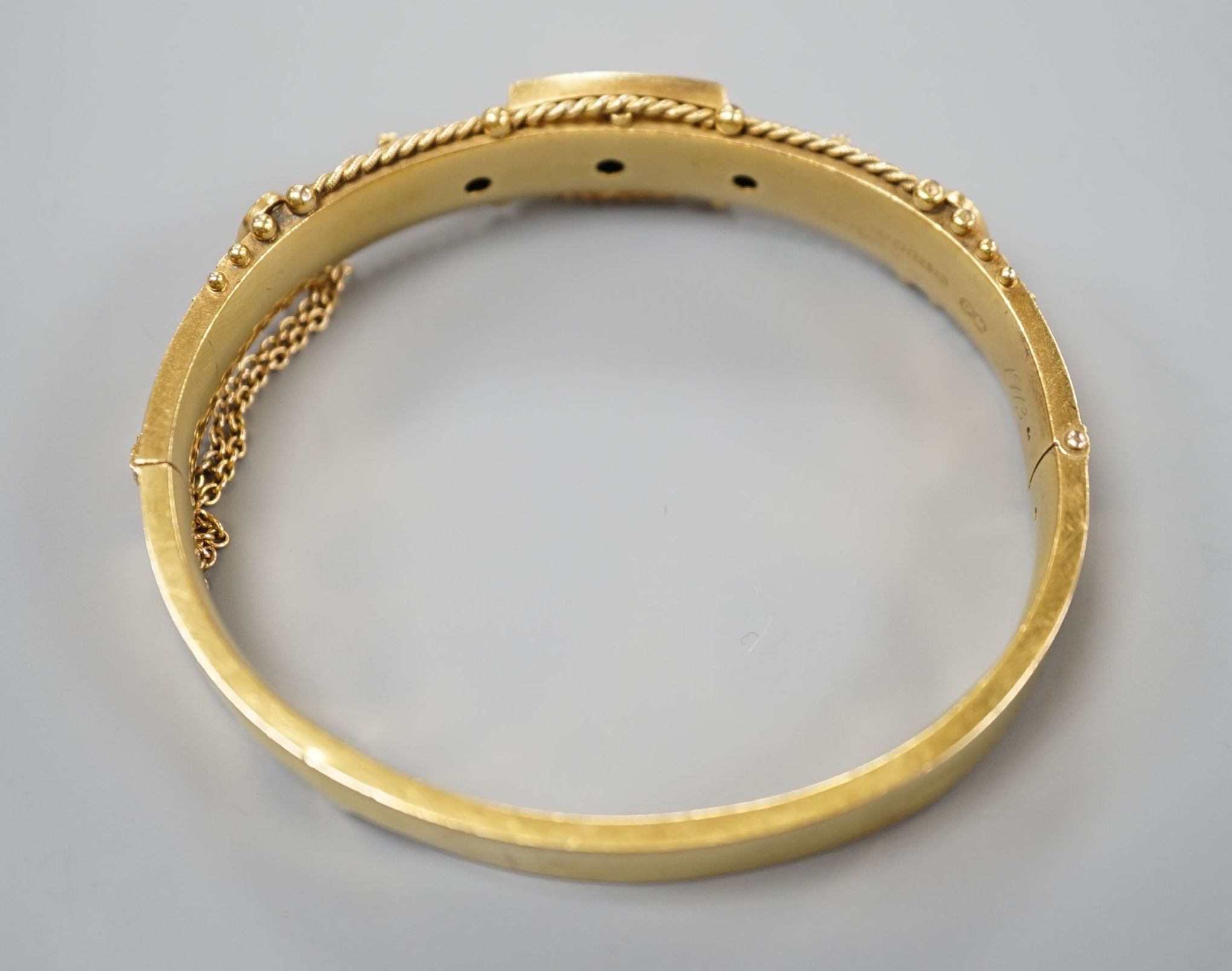 An Edwardian 15ct gold and three stone diamond set hinged bangle, interior diameter 57mm, gross weight 15.8 grams.